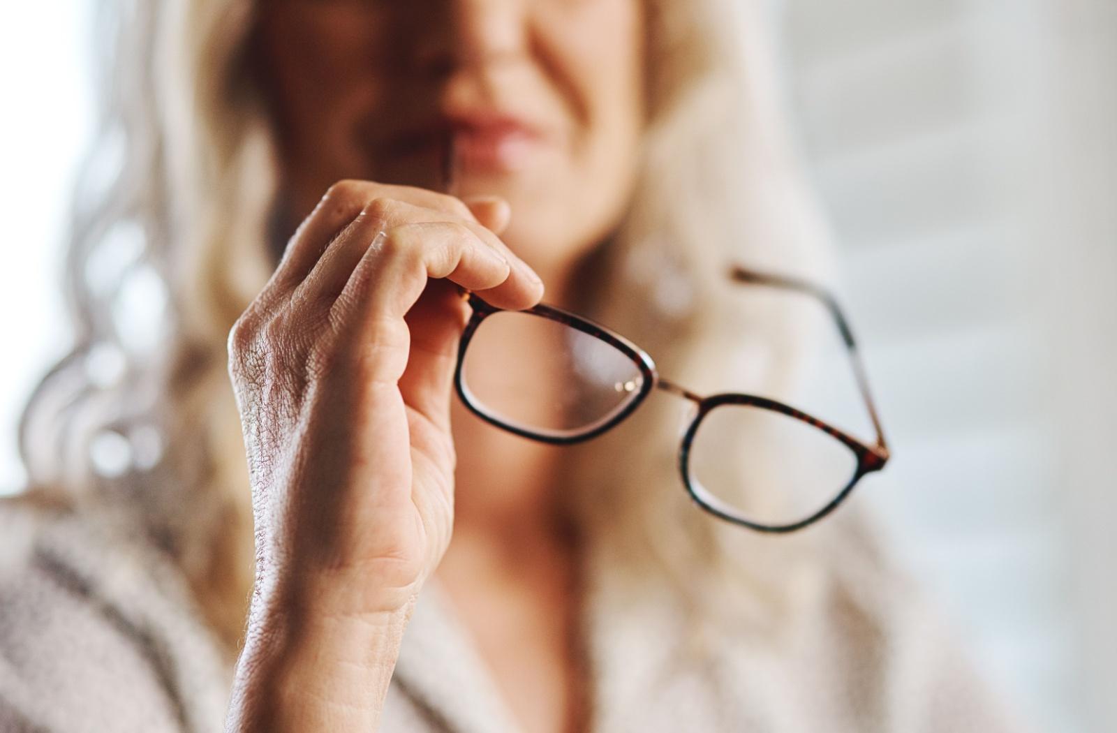 A person looking closely at their glasses